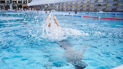 Ein Kind springt in einem Schwimmbad ins Becken.