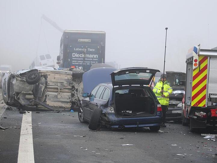Demolierte Fahrzeuge stehen an einer Unfallstelle auf der A7 auf einer Brücke im Nebel. Foto: Karl-Josef Hildenbrand/dpa