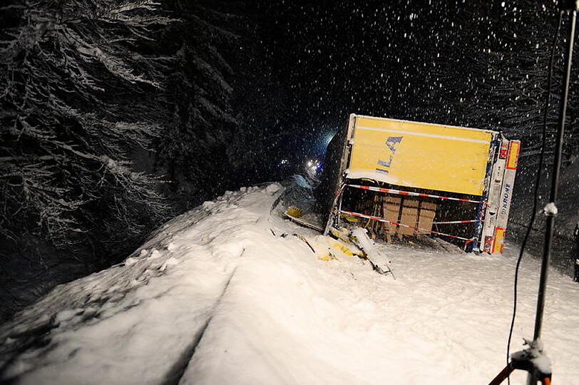 Ein LKW kommt auf schneeglatter Fahrbahn ins Rutschen und kippt um