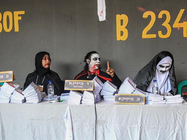 Helferinnen und Helfer amüsieren sich in Gruselkostümen in einem Wahllokal in Jakarta.