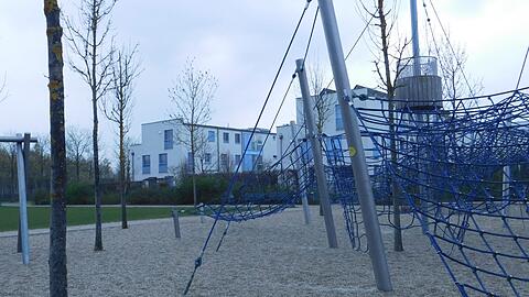 Vorne der Spielplatz, hinten Grünstreifen und Hecke.