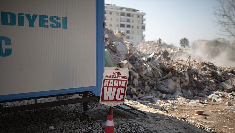 Eine von der Gemeinde Kayseri bereitgestellte mobile Toilette für Frauen steht neben einem eingestürzten Gebäude im türkischen Kahramanmaras.