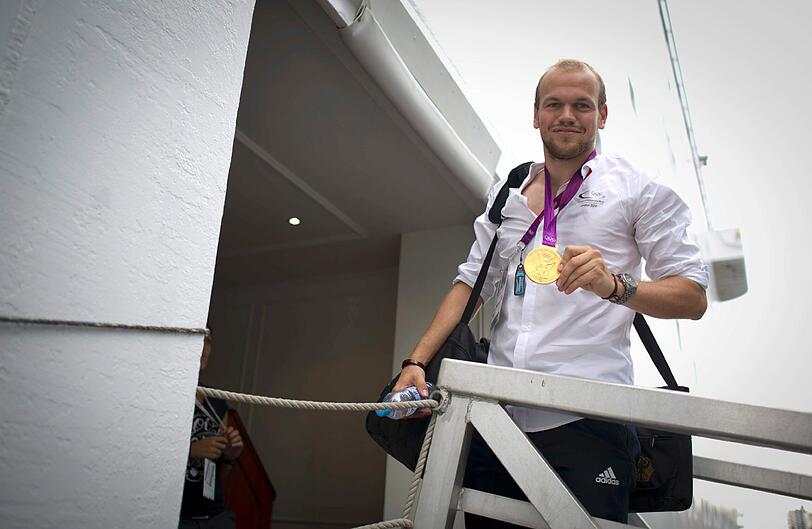 Der Hockeyspieler Thilo Stralkowski posiert mit seiner Goldmedaille beim Betreten auf die MS Deutschland.