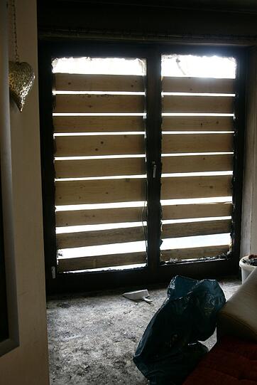 Im Inneren der Wohnung: Fensterscheiben sind durch die Hitze geborsten, überall sind Rußrückstände sichtbar.