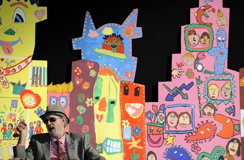 Hier sind man Rizzi vor einer Bilderwand aus einem Malwettbewerb von Bremer Schulen.