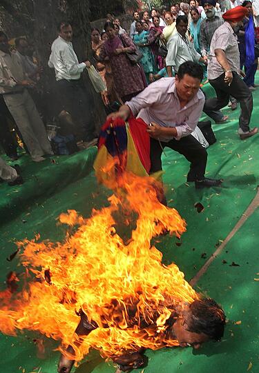 Auf einer Demonstration in Indien löscht ein Teilnehmer einen tibetischen Aktivisten, der sich selbst in Brand gesteckt hat.