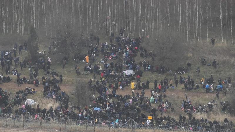 Menschen stehen hinter einem Grenzzaun in Belarus in der Nähe des polnisch-belarussischen Grenzübergangs in Kuznica.