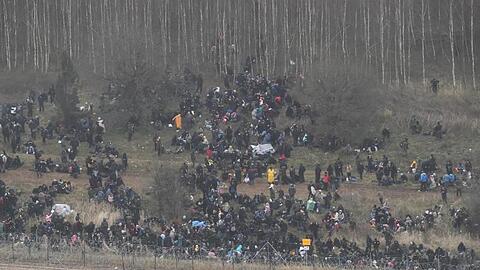 Menschen stehen hinter einem Grenzzaun in Belarus in der Nähe des polnisch-belarussischen Grenzübergangs in Kuznica.
