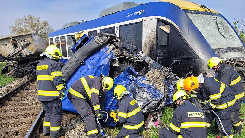 Feuerwehrleute arbeiten am Ungl&uuml;cksort, wo ein Personenzug und ein Lastwagen zusammengesto&szlig;en sind. Bei dem Ungl&uuml;ck kam eine Person ums Leben, 21 Menschen wurden verletzt.
