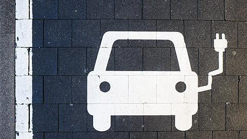 Ein Symbol markiert einen Parkplatz an einer Ladesäule für Elektroautos.