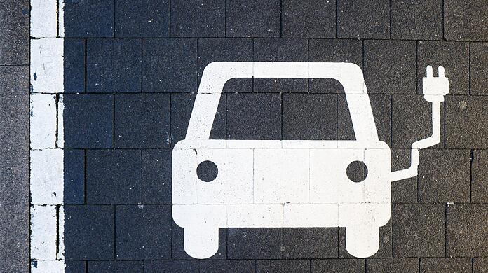 Ein Symbol markiert einen Parkplatz an einer Ladesäule für Elektroautos.
