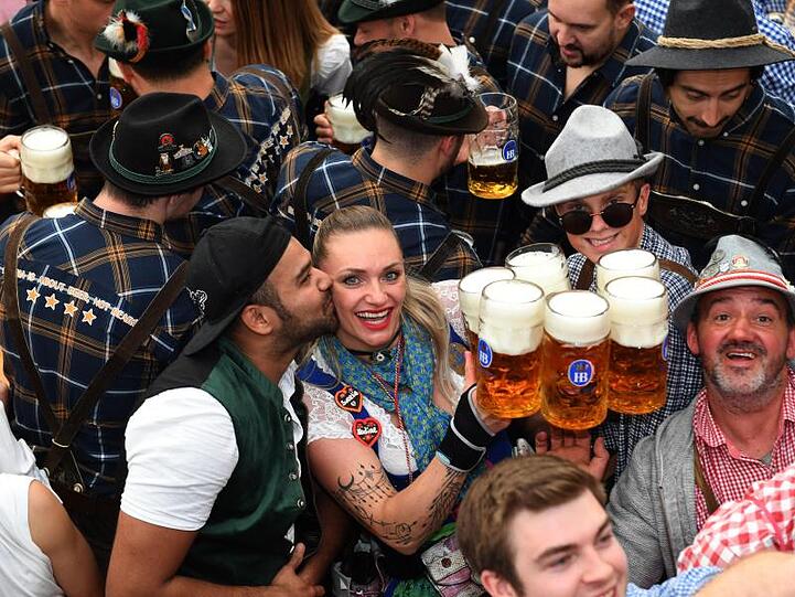 Eine Bedienung bekommt im Hofbräuzelt von einem Gast einen Kuss, während sie Bierkrüge zu Gästen bringt.