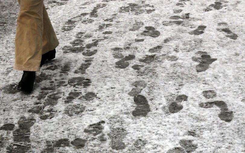 Eine Fußgängerin geht am 31.03.2015 in Berlin-Mitte über einen verschneiten Bürgersteig.