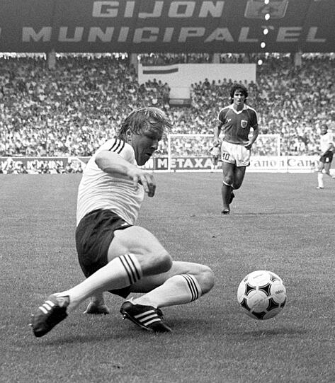 Horst Hrubesch geht mit letztem Einsatz zum Ball, der österreichische Mittelfeldspieler Reinhold Hintermaier schaut aus der Distanz. Die deutsche Nationalmannschaft führt im WM-Spiel gegen Österreich durch ein frühes Tor mit 1:0.