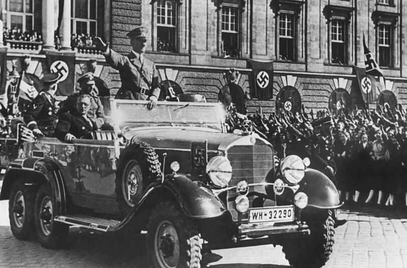 In einem Auto stehend grüßt Adolf Hitler am 14.03.1938 in Wien, Österreich, die ihm zujubelnde Menschenmenge.