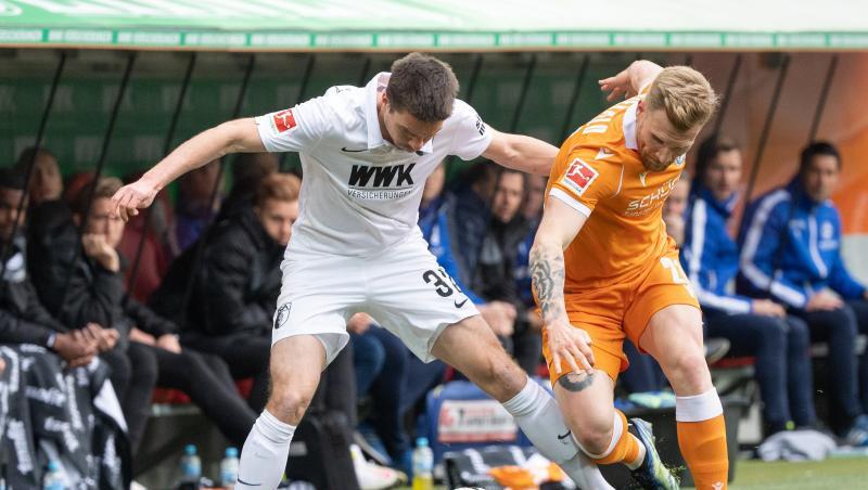 Augsburgs Raphael Framberger (l) und Bielefelds Andreas Voglsammer kämpfen an der Seitenauslinie um den Ball.