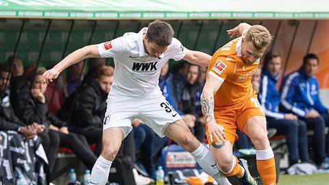 Augsburgs Raphael Framberger (l) und Bielefelds Andreas Voglsammer kämpfen an der Seitenauslinie um den Ball.
