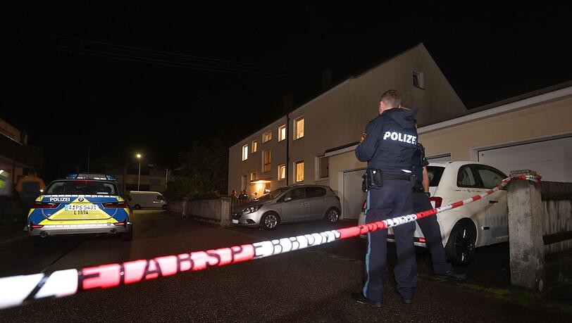 Polizisten am Tatort vor dem Haus in Langweid, in dem drei Menschen erschossen wurden.