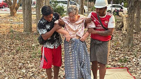 Rettungskräfte helfen einer verletzten Frau, die nach einem Erdbeben unter einem Gebäude eingeschlossen war.