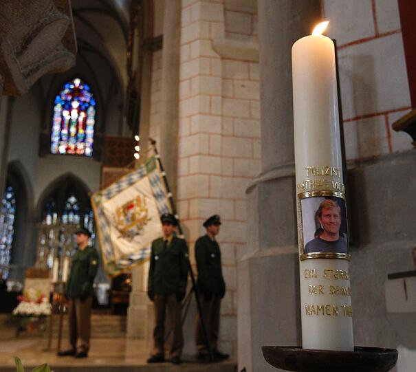 Bei der Trauerfeier im Augsburger Dom brennt eine Kerze mit dem Foto von Matthias V..