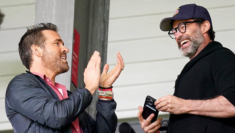 Ryan Reynolds (li.) und Hugh Jackman gut gelaunt auf der Stadiontribüne.