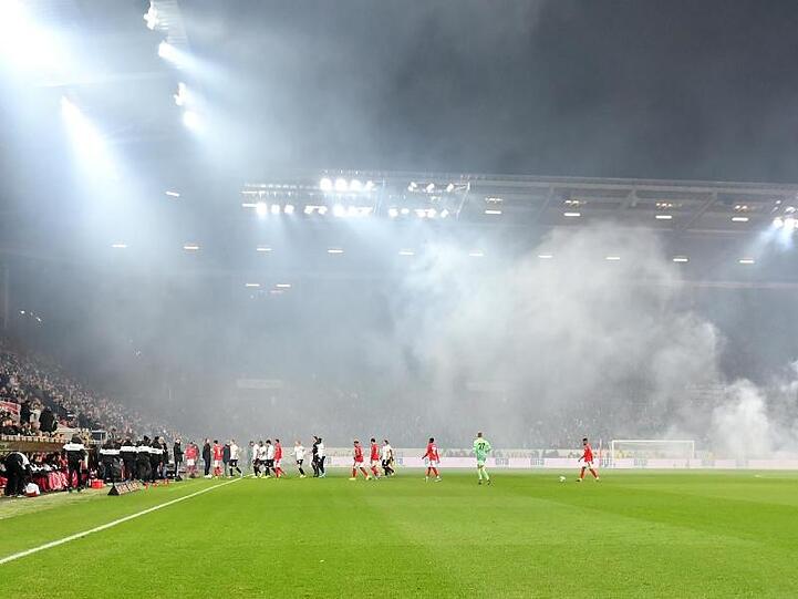 Dichte Rauchschwaden durchziehen das Stadion, nachdem Feuerwerkskörper aus dem Frankfurter Fanblock auf dem Rasen gelandet sind.