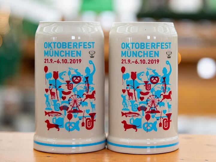 Name und Zeitraum des Oktoberfestes 2019 stehen auf zwei Examplaren des offiziellen Wiesn-Maßkrugs. Foto: Sven Hoppe/Archiv