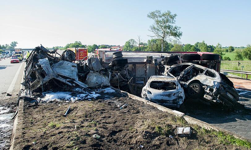 Rettungskräfte auf der Autobahn A8 bei Sulzemoos (Oberbayern) an einem ausgebrannten Lastwagen. Zwei weitere Autos sind in den Auflieger des Lastwagens gefahren. Bei dem Unfall kam mindestens eine Person ums Leben.