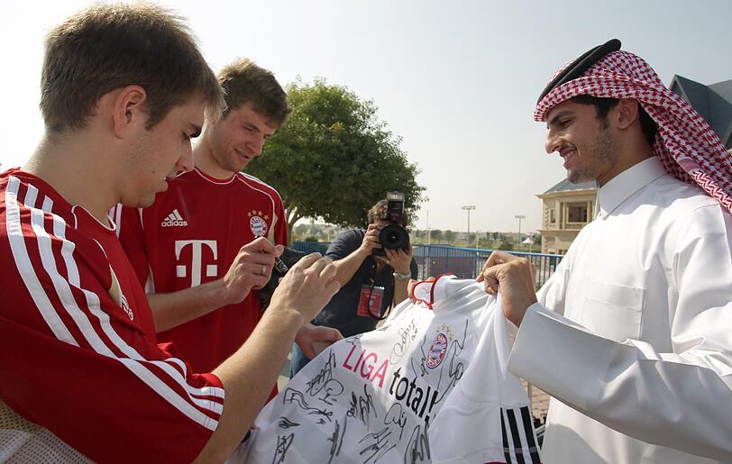 Archiv: Bayernspieler Philipp Lahm (l) und Thomas Müller geben in Doha (Katar) einem einheimischen Fan Autogramme auf ein Bayerntrikot.