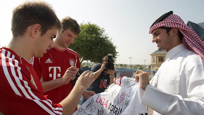 Archiv: Bayernspieler Philipp Lahm (l) und Thomas Müller geben in Doha (Katar) einem einheimischen Fan Autogramme auf ein Bayerntrikot. Archiv: Bayernspieler Philipp Lahm (l) und Thomas Müller geben in Doha (Katar) einem einheimischen Fan Autogramme auf ein Bayerntrikot.