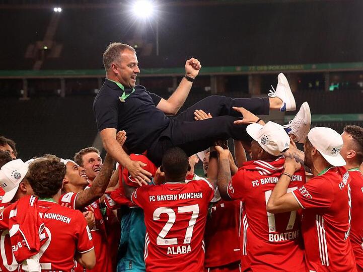 Münchens Trainer Hansi Flick wird von seinen Spielern in die Luft geworfen.