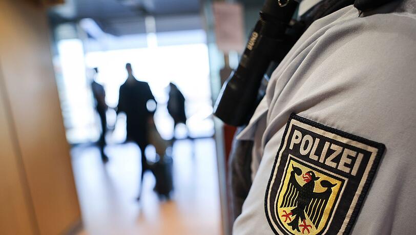 Ein Beamter der Bundespolizei kontrolliert Reisende am Flughafen.