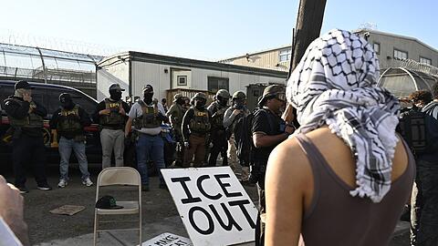 Vor Bundesbeamten der Einwanderungsbeh&ouml;rde ICE haben Demonstrierende ein gro&szlig;es Schild mit der Aufschrift "ICE out" drapiert.