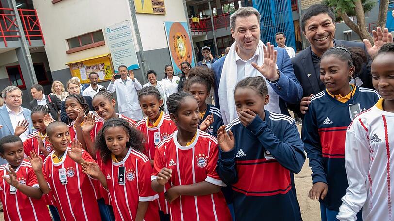 Den Kindern der "German Church School" haben Söder und Ex-Fußballer Giovane Elber Trikots des FC Bayern mitgebracht.