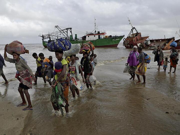 Familien kommen, nachdem sie 200 Kilometer vor Beira, aus einem überschwemmten Gebiet mit dem Boot gerettet wurden, am Strand an.
