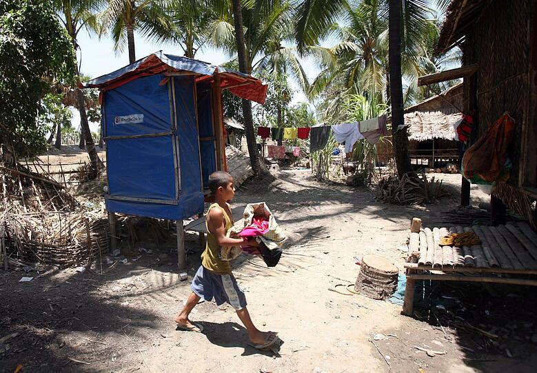 Zwei Jahre nachdem der Zyklon "nargis" Myanmar getroffen hat, leben die Menschen noch immer in Trümmern. Eine Junge läuft mit seinen Kleidern in Richtung Toilette, die von der "Save the Children Organization" gespendet wurde.