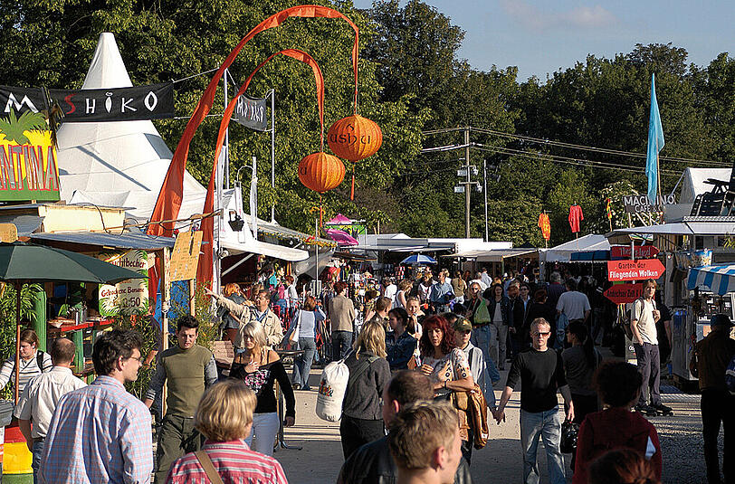 Das alltägliche Tollwood-Gewusel zwischen Essensständen und Kleider- bis Kopfmassagengeräte-Verkäufern, zwischen Garten-Bars und Marktzelten.