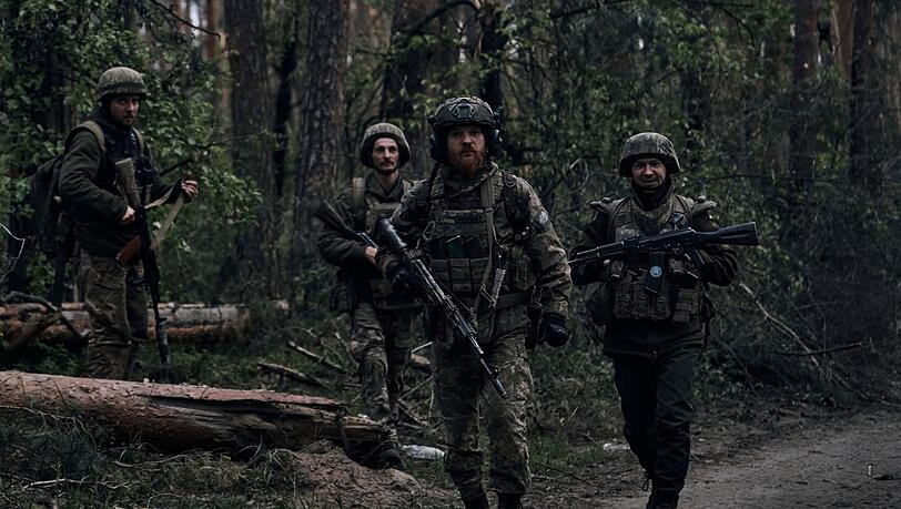 Ukrainische Soldaten gehen in der Nähe der russischen Stellungen in der Region Luhansk durch den Wald.