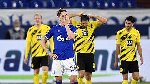 Schalkes Bastian Oczipka (vorne) steht enttäuscht im Vordergrund - im Hintergrund feiern die Dortmunder das zweite Tor ihrer Mannschaft.