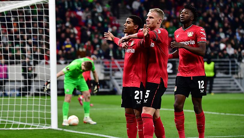 Leverkusens Torschütze Amine Adli (l-r) jubelt nach seinem Tor zum 0:2 mit Mitchel Bakker und Edmond Tapsoba.