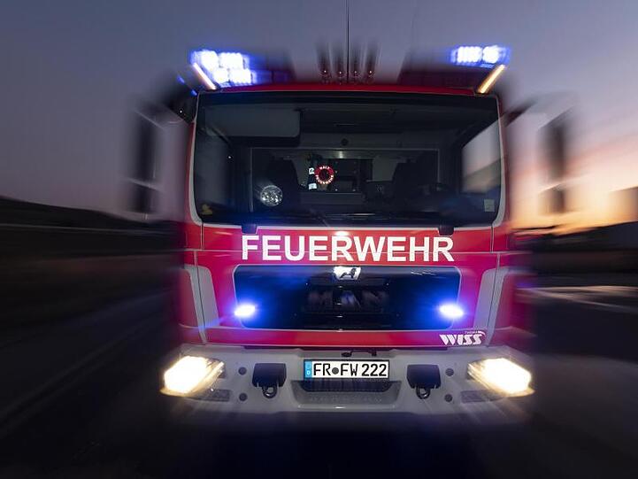 Ein Feuerwehrfahrzeug steht mit eingeschaltetem Blaulicht im Sonnenuntergang auf einer Straße. Foto: Patrick Seeger/dpa/Archivbild