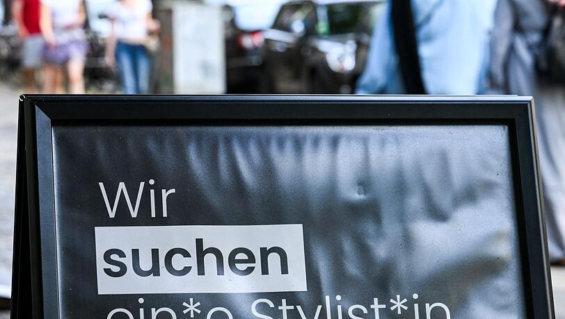 Auf einem Schild wird gendergerecht eine Stylistin beziehungsweise ein Stylist gesucht.