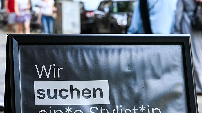 Auf einem Schild wird gendergerecht eine Stylistin beziehungsweise ein Stylist gesucht.