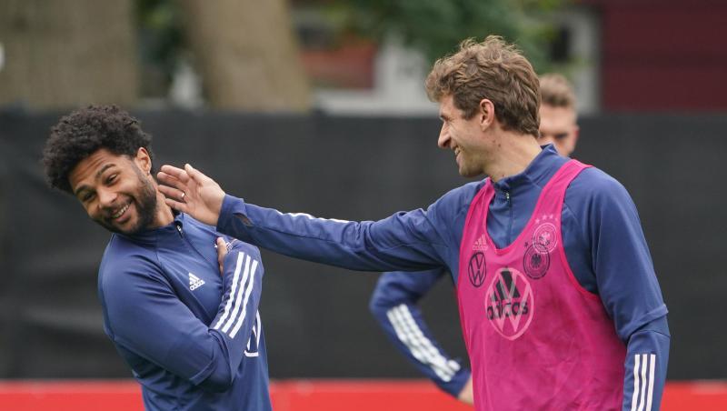 Thomas Müller (r) schertzt im Training mit Serge Gnabry.