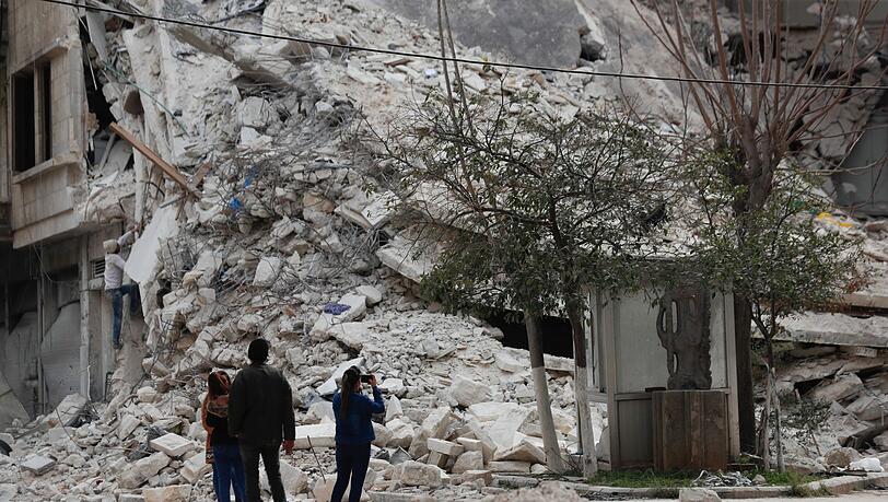 Menschen stehen vor den Trümmern eines Gebäudes, das bei dem jüngsten Erdbeben in Aleppo zerstört wurde.