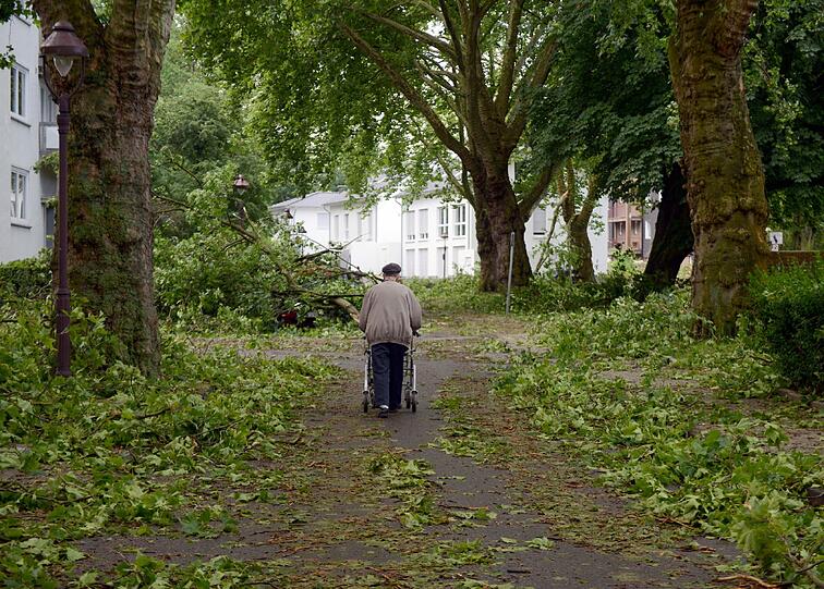 Ein Mann geht mit seinem Rollator in Gelsenkirchen (Nordrhein-Westfalen) nach dem Mega-Unwetter über eine Straße.
