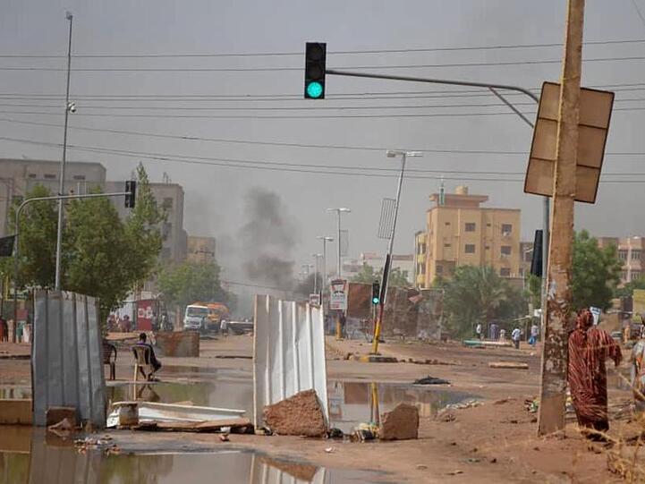 Rauch steigt in Khartum hinter einer Straßenbarrikade auf, die Militärfahrzeuge am Durchkommen hindern soll.