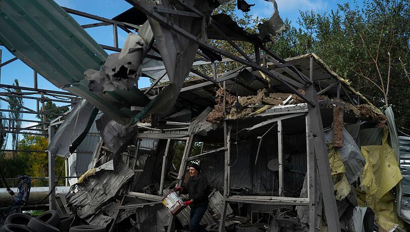 Nach dem russischen Raketenangriff löscht ein Mann in Saporischschja die Überreste eines Feuers in einer zerstörten Autowerkstatt.