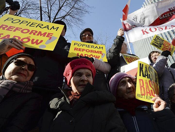 Unterstützer der rechten Regierung Polens halten auf einer Demonstration für eine Justizreform Plakate in die Höhe (Archiv).