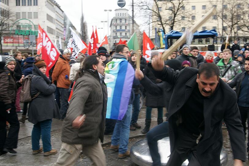 Mit voller Wucht schlägt dieser Mann am Stachus zu. Der Stock seines Demo-Schilds ist bereits abgebrochen.